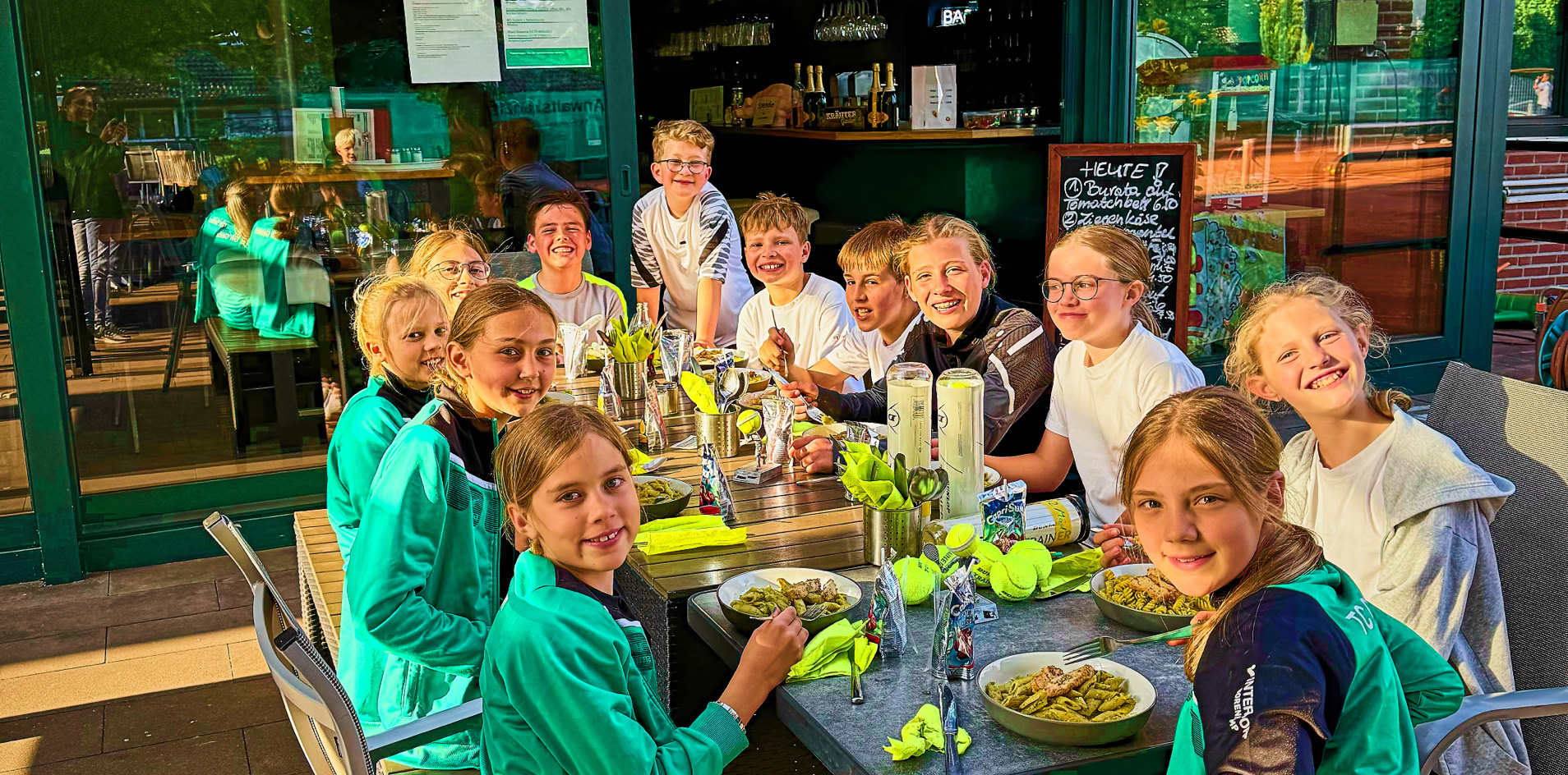 Eine Gruppe von Personen sitzt an einem Tisch im Freien und isst zusammen.