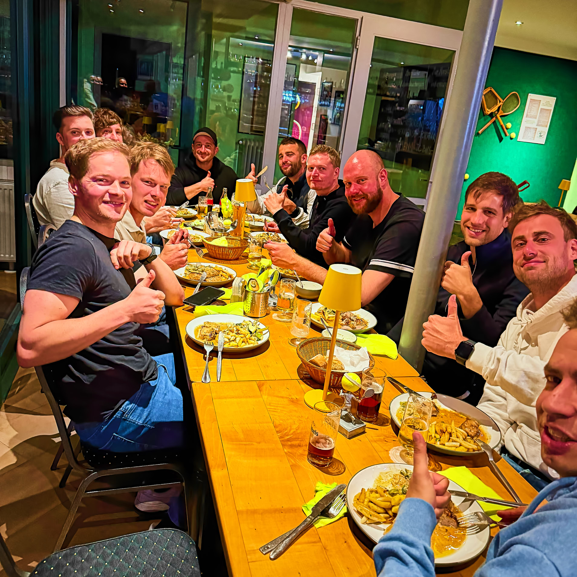 Eine Gruppe von Menschen sitzt an einem langen Tisch in einem Restaurant und isst.