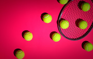 Tennisb&auml;lle und ein Tennisschl&auml;ger auf einem pinken Hintergrund.