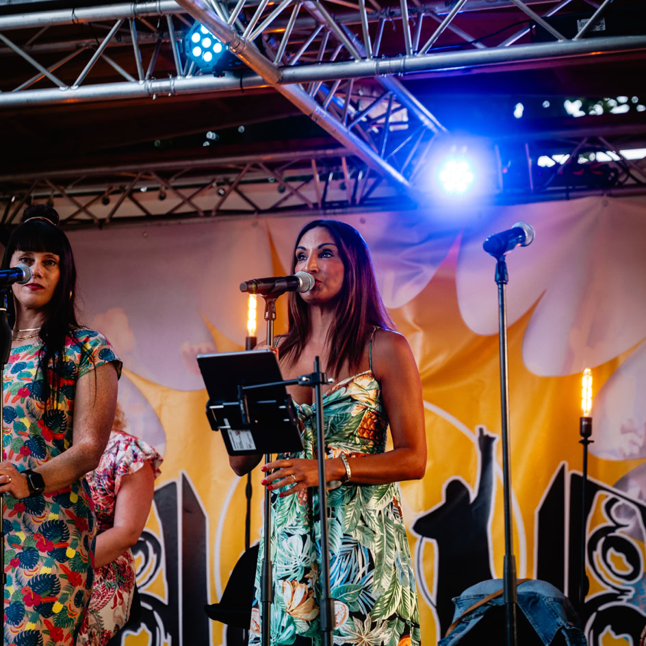 Zwei Personen stehen auf einer B&uuml;hne mit Mikrofonen, umgeben von bunten Lichtern und Dekorationen.