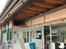 Geb&auml;ude mit ge&ouml;ffneter Fassade, Leitern, Werkzeugen und Baumaterialien im Vordergrund.