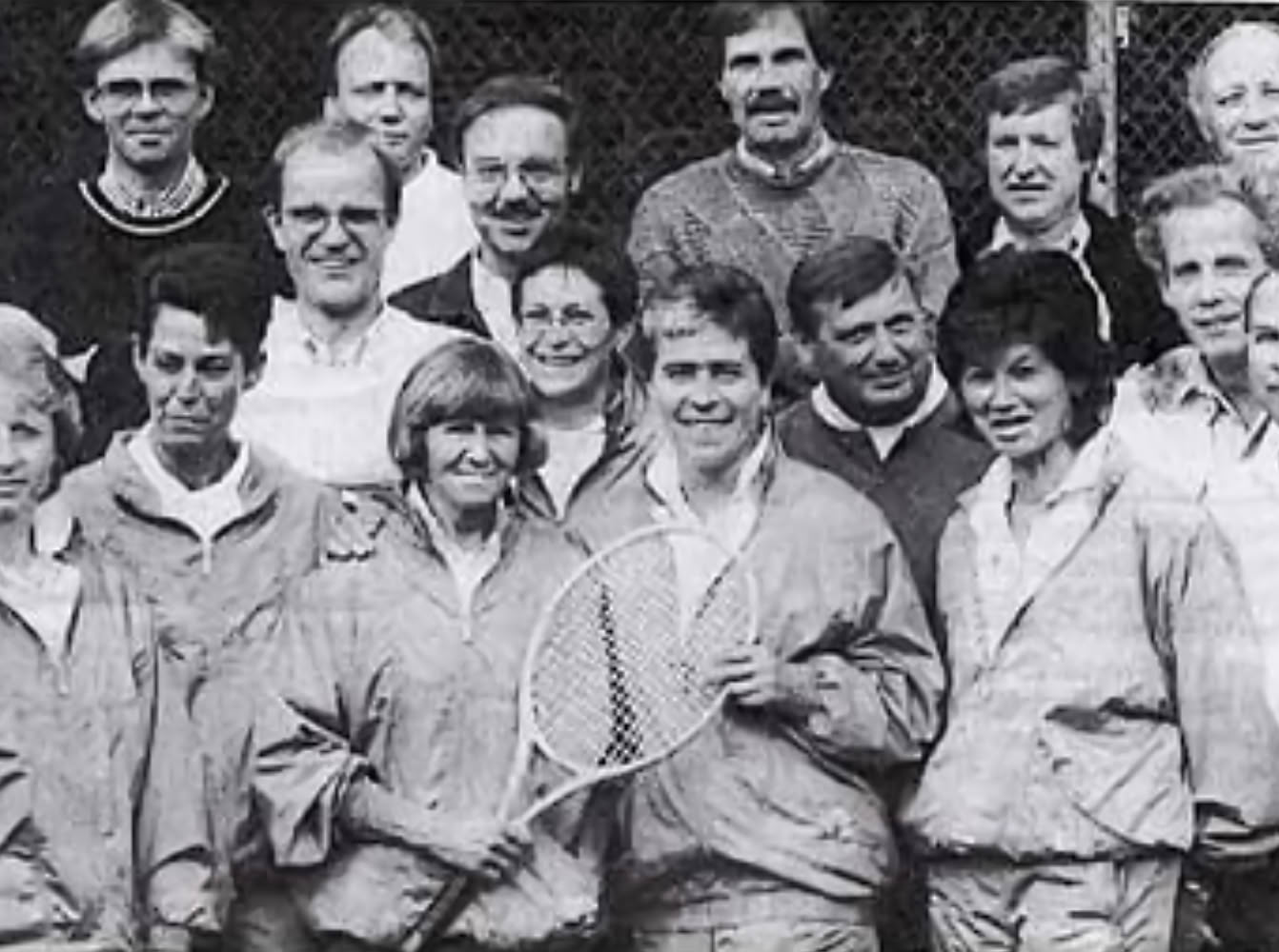 Eine Gruppe von Menschen in Sportkleidung, einige halten Tennisschl&auml;ger.