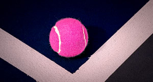 Ein pinker Tennisball liegt auf einem dunkelblauen und wei&szlig;en Boden mit geometrischen Linien.
