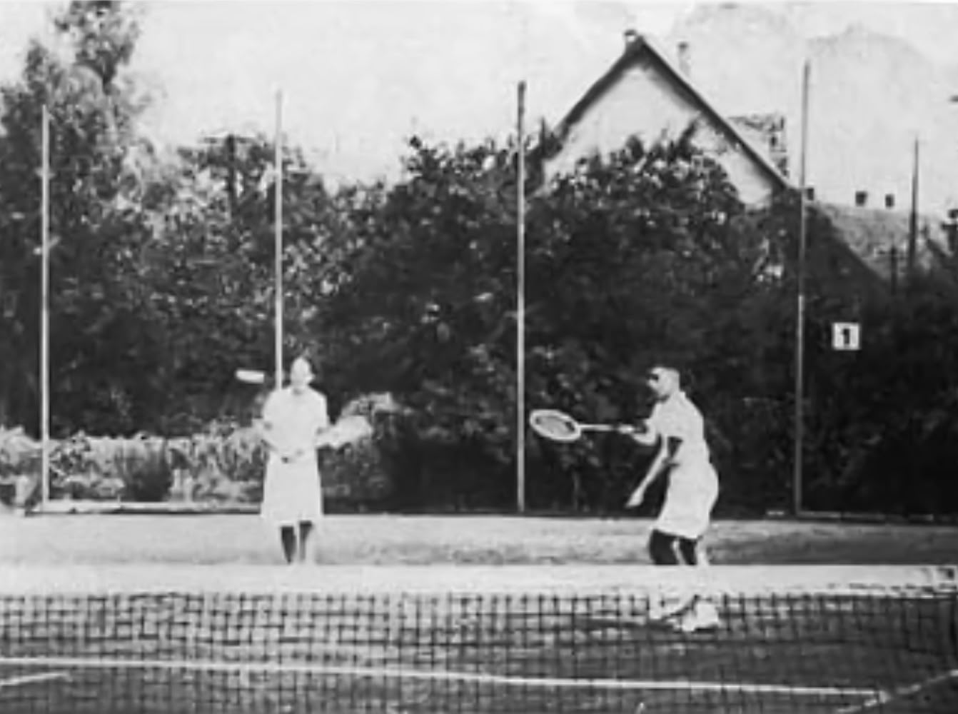 Vier Personen in Tennisbekleidung stehen auf einem Tennisplatz und halten Tennisschl&auml;ger.