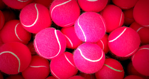 Mehrere pinke Tennisb&auml;lle mit wei&szlig;en Linien.