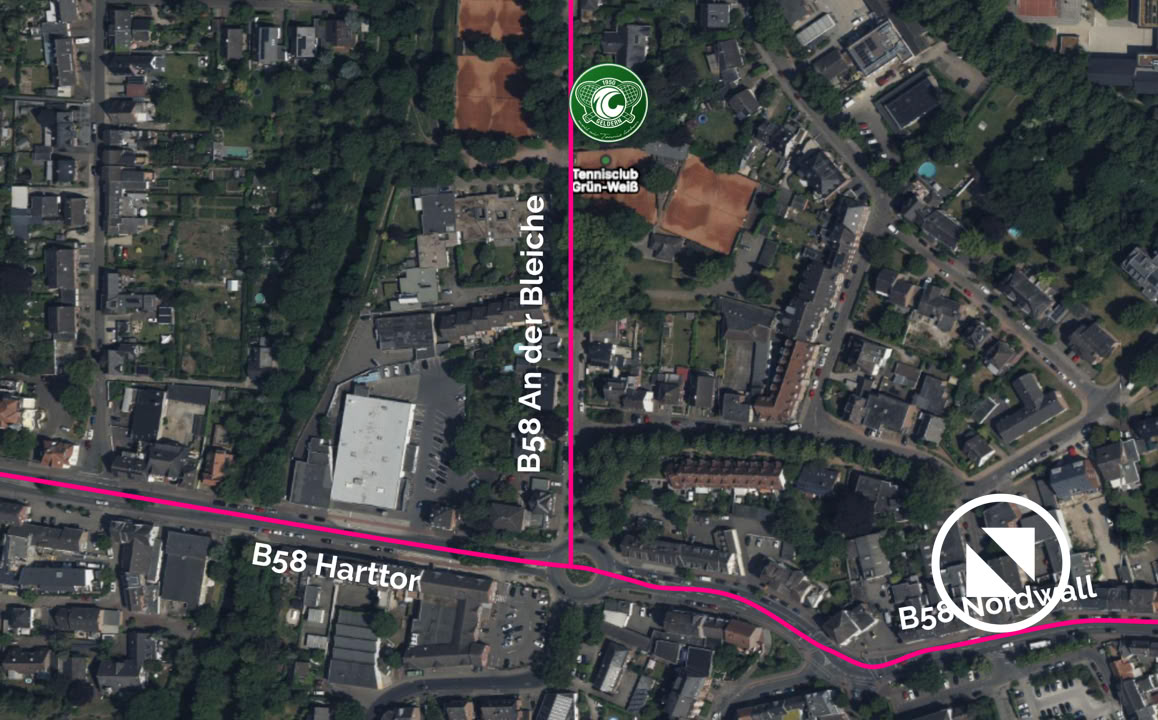 Satellitenansicht einer Stadt mit Stra&szlig;en, Geb&auml;uden und Gr&uuml;nfl&auml;chen. Ein gr&uuml;nes Symbol ist auf einer Stra&szlig;e markiert.