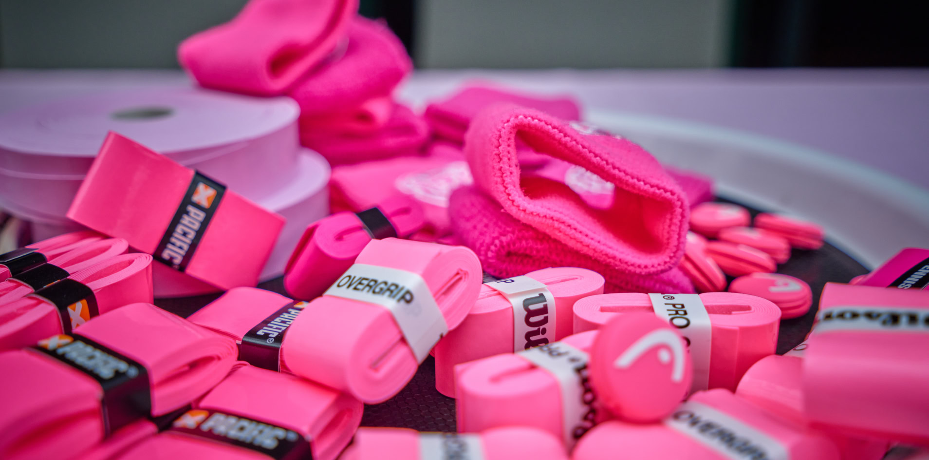 Ein Tablett mit mehreren pinken Sportartikeln, darunter Handgelenkbandagen und Schwei&szlig;b&auml;nder.